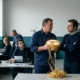 Tecnico che trattiene un diamante avvolto in filamenti dorati sfilacciati fino a terra, simbolo del monopolio del know-how in azienda, mentre il titolare ascolta a braccia conserte.